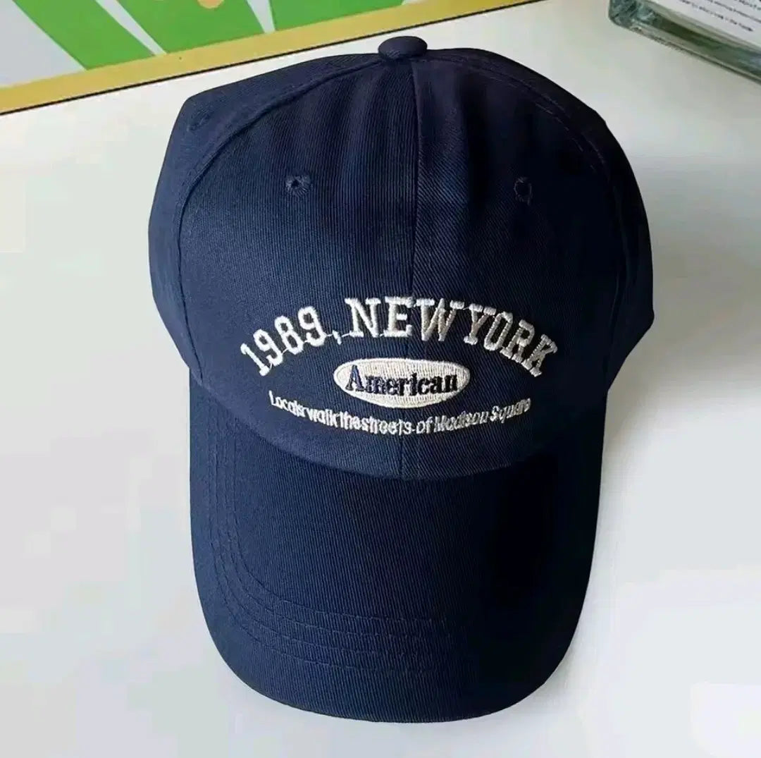 Navy blue cap with '1989 New York' and 'American' text on a white surface in Pakistan by Caps Nation