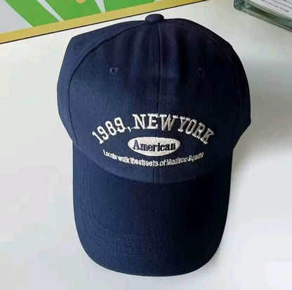Navy blue cap with '1989 New York' and 'American' text on a white surface in Pakistan by Caps Nation