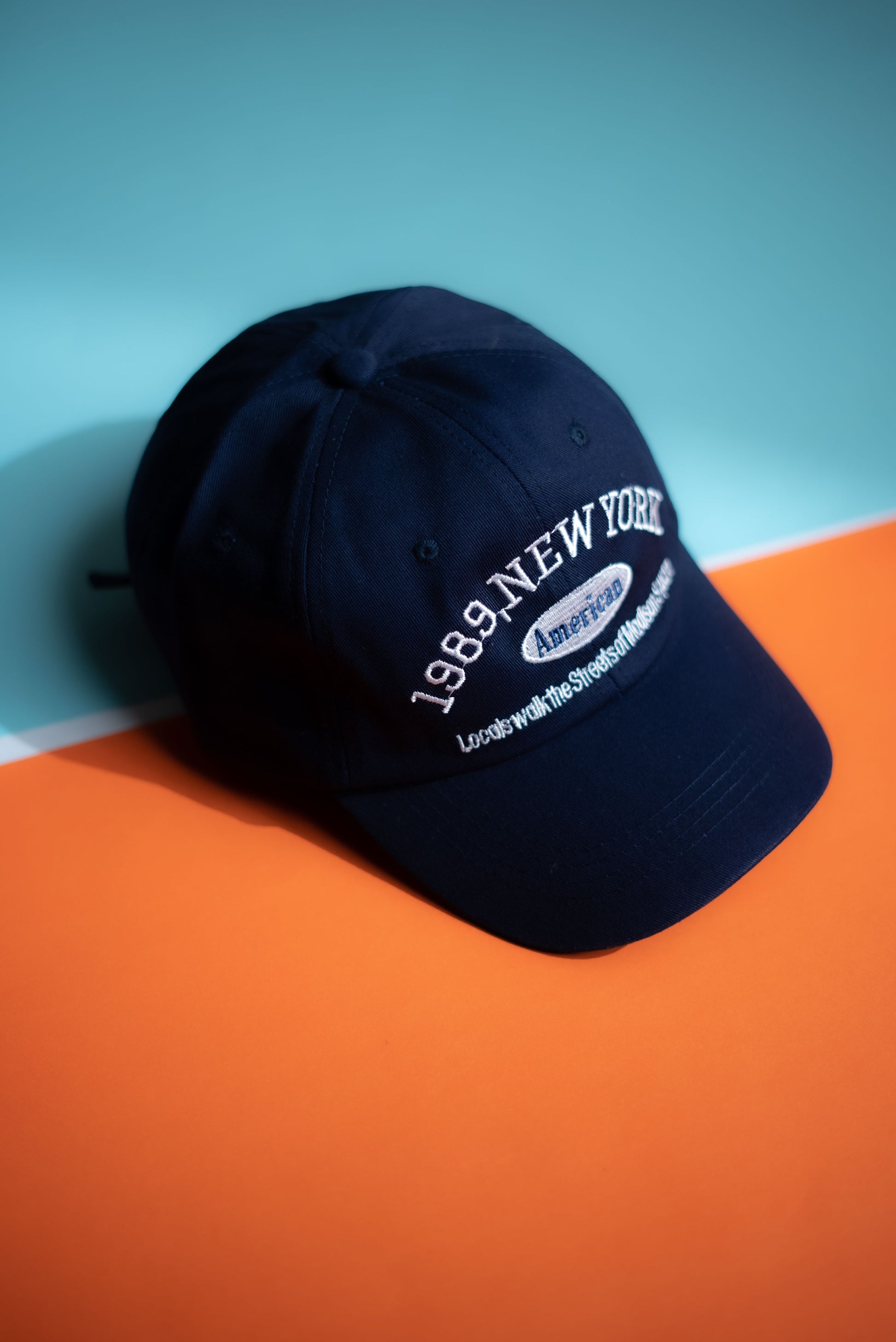 Navy blue cap with white text on an orange and blue background  in Pakistan by Caps Nation