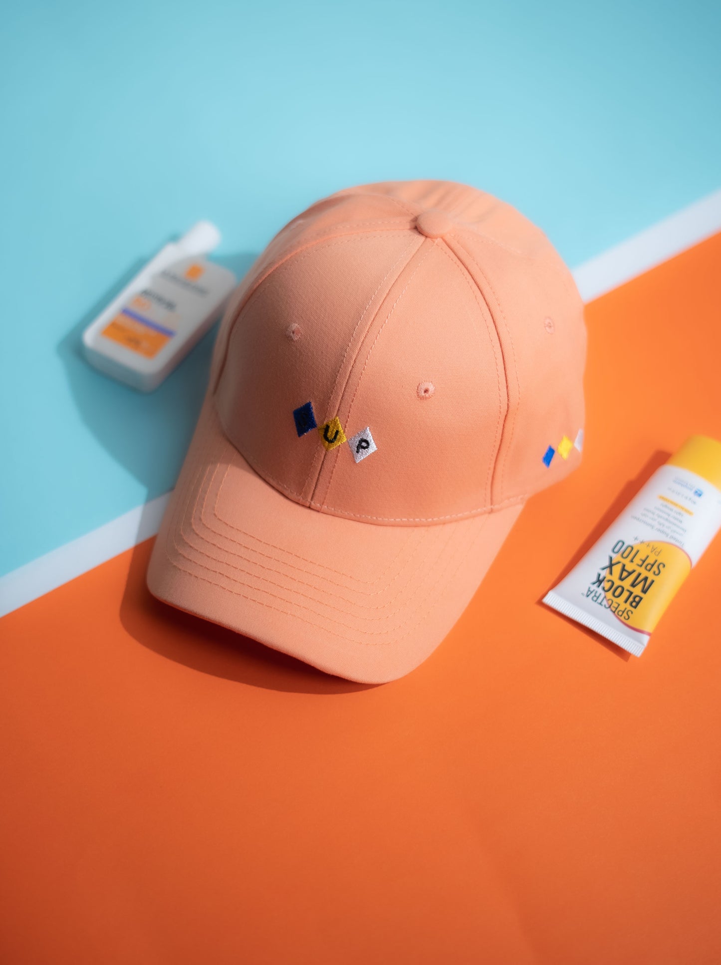 Orange cap with small logos on a blue and orange background in Pakistan by Caps Nation