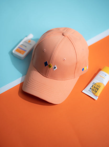 Orange cap with small logos on a blue and orange background in Pakistan by Caps Nation
