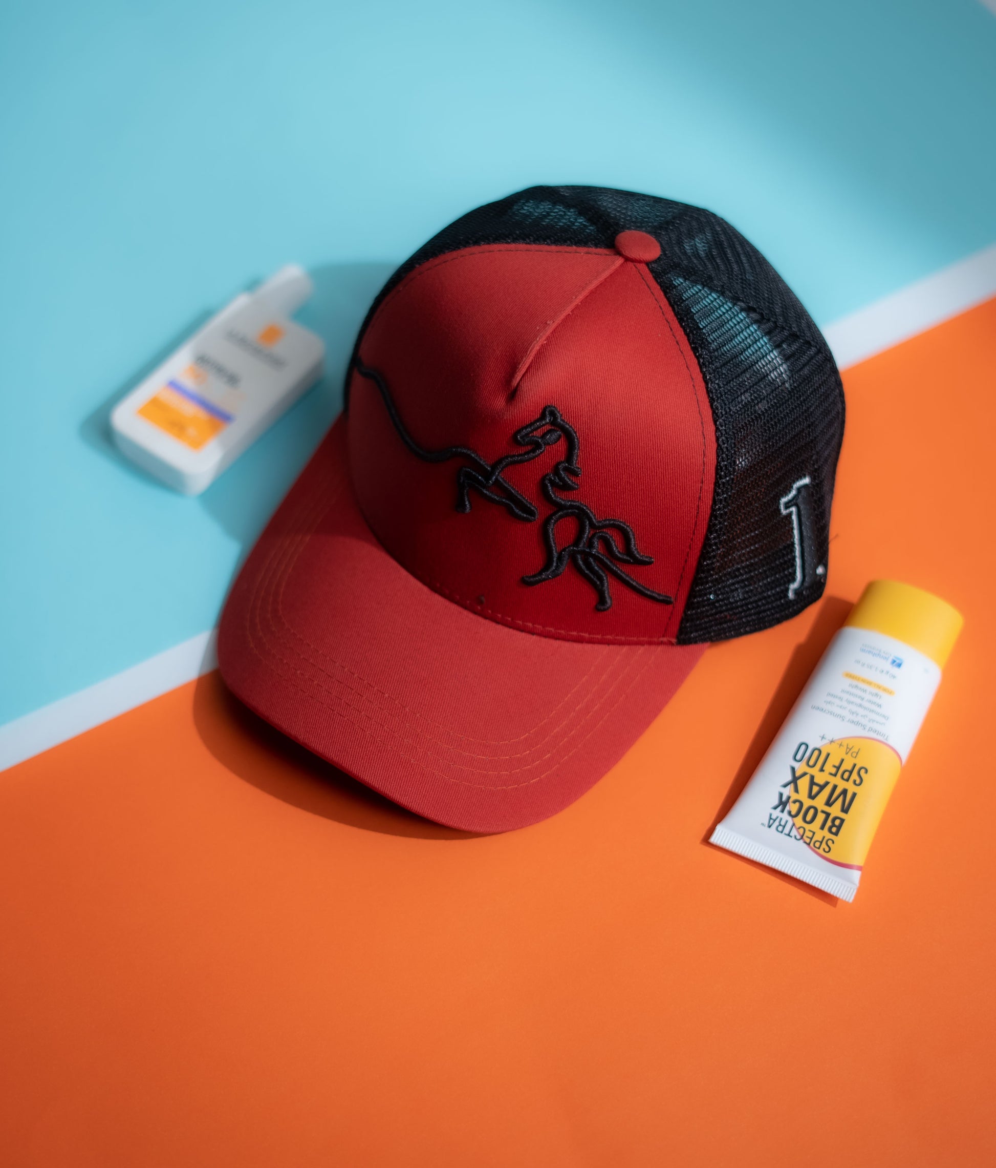 Red and black cap with a logo on an orange and blue background in Pakistan by Caps Nation