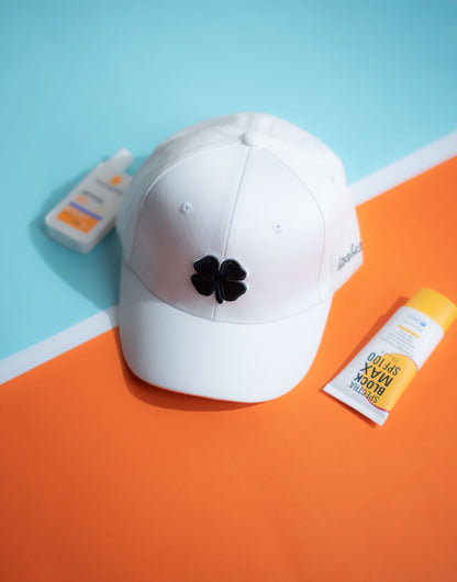 White cap with a black clover design on an orange and blue background in Pakistan by Caps Nation