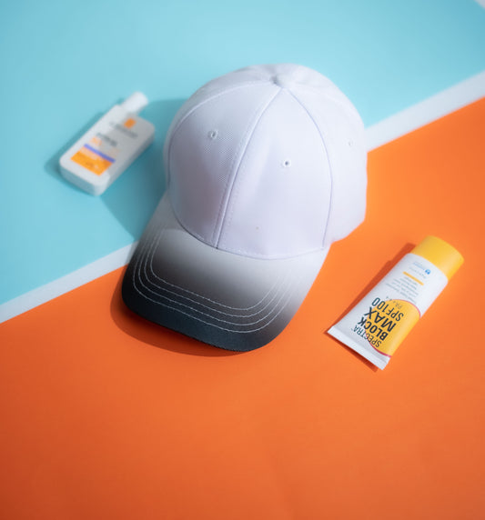 White cap and sunscreen bottles on a colorful geometric background 
