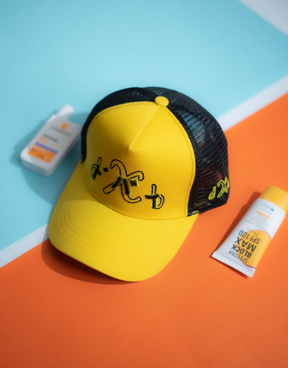 Yellow cap with black mesh back on a colorful geometric background in Pakistan by Caps Nation
