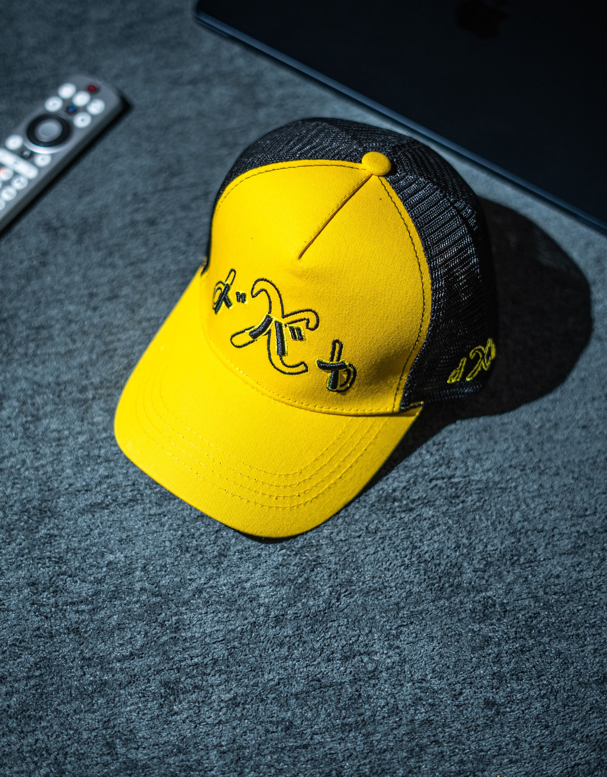 Yellow cap with black text on a dark textured surface in Pakistan by Caps Nation